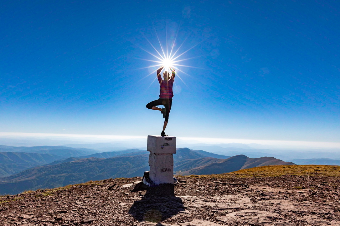 Yoga auf dem Grenzstein mit Sonnenstern. Auf dem Berg Midzor - Grenze zwischen Bulgarien und Serbien