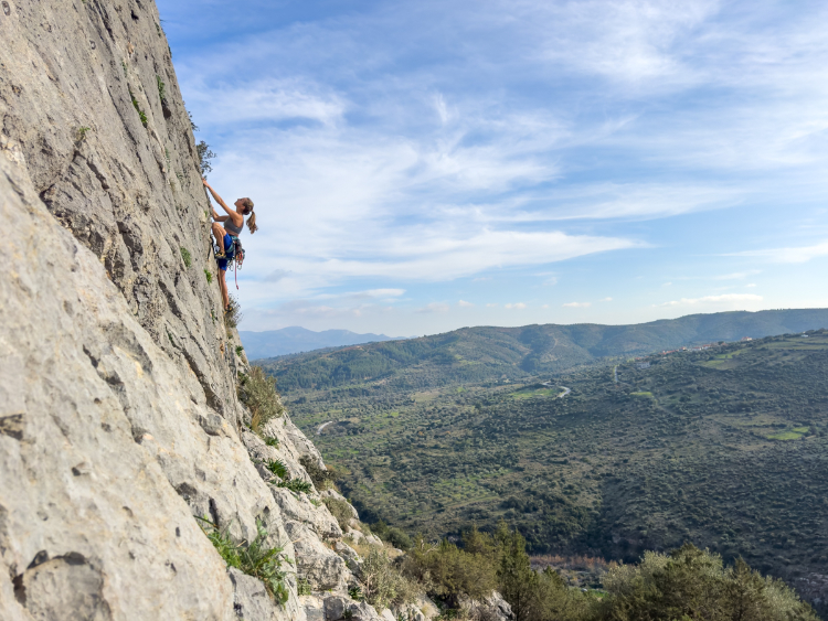 Kletterin am strukturierten Fels bei bestem Wetter in Manikia, in Griechenland