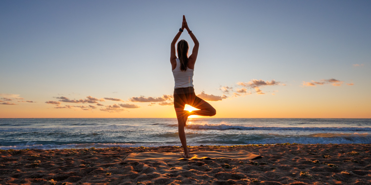 Yogalehrerin am Strand mit Sonne mit Vrksasana, der Baumpose - am Schwarzem Meer in Bulgarien