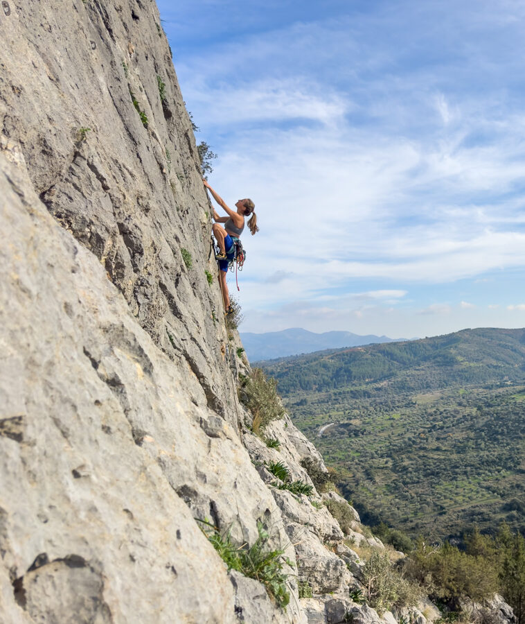 Kletterin am strukturierten Fels bei bestem Wetter in Manikia, in Griechenland