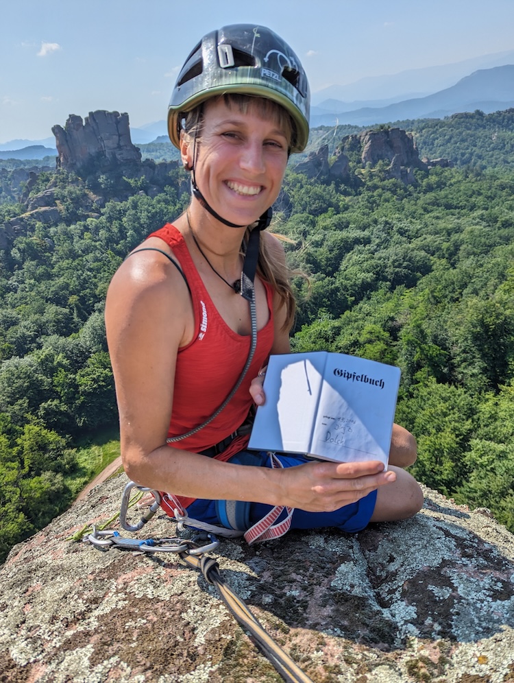 Julia- Kletterlehrerin auf dem Dolch Gipfel mit Gipfelbuch in der Hand in Belogradtschik, Bulgarien.